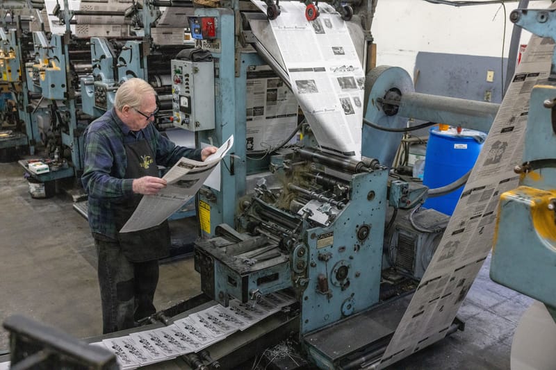 Tom Forney examines the May 30th edition of The Mountain Messenger for defects as it comes off the press