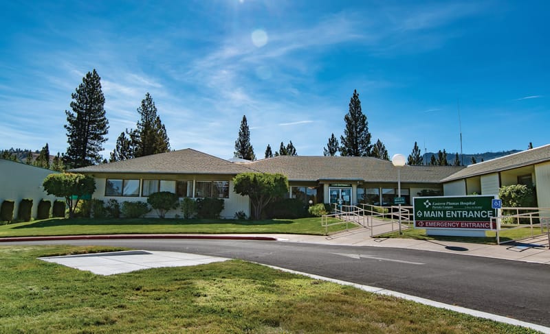 Eastern Plumas Health Care’s Portola hospital entrance, with an accessible ramp and signs for the main and emergency entrances.