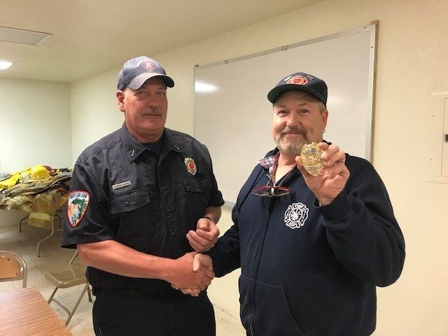 Long-time Pike City Fire Chief Jim Buckbee (right) shows off the Chief’s badge before passing it over to incoming Chief Chris Dorn (left) on September 18, 2019