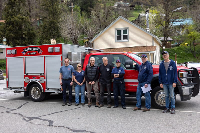 Members of the Downieville Fire Department in front of one of its fire engines and the newly purchased property planned to house it.