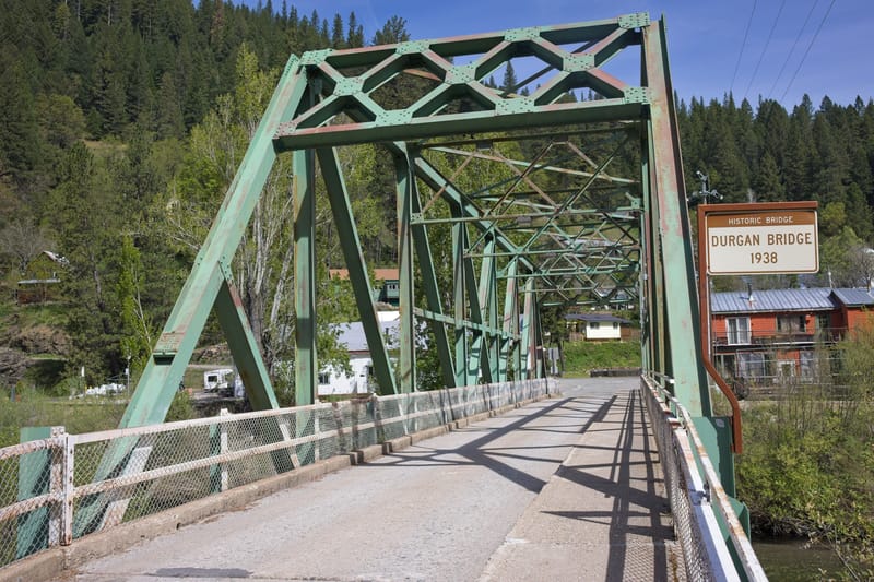 The green steel truss of Durgan Bridge spans the roadway beside a sign identifying the bridge.