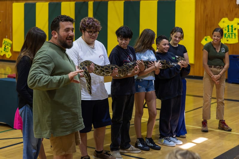 Students hold a 13-foot Burmese python.
