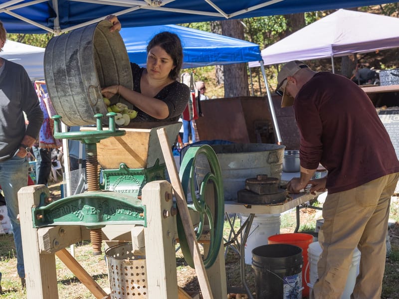 Apples being cut and fed into a cider press at the 2024 AppleFest.