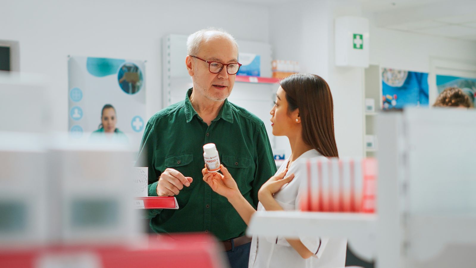 A pharmacist converses with an elderly patient.